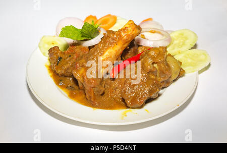 Popular Indian meal of spicy mutton gravy popularly known as mutton kosha with chili and sliced vegetables. Stock Photo