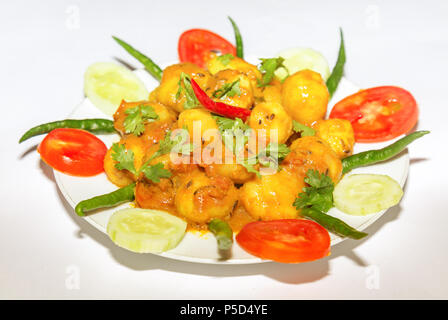 Spicy Indian vegetarian food prepared with small potatoes popularly known as Dum Aloo garnished with cucumber, tomato and green chili. Stock Photo