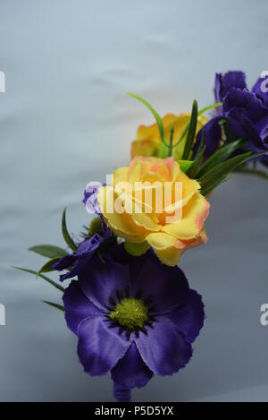 Women's interesting hair decoration, festive look. Beautiful head hoop made of blue, yellow flowers and green leaves placed on white background. Stock Photo