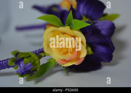 Women's interesting hair decoration, festive look. Beautiful head hoop made of blue, yellow flowers and green leaves placed on white background. Stock Photo