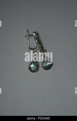 Jewelry, women's silver earrings with blue stones arranged on white background. Stock Photo