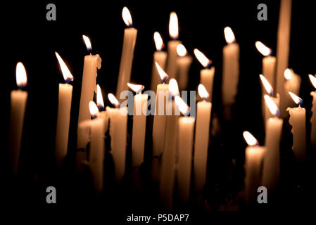 Many burning candles - Light of candels in the church on the black background Stock Photo