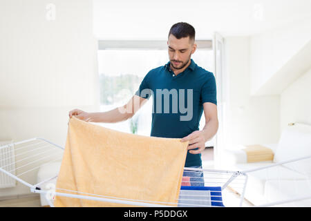 man taking laundry from drying rack at home Stock Photo
