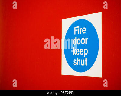 Fire door Keep Shut Sign on a Red Door Stock Photo