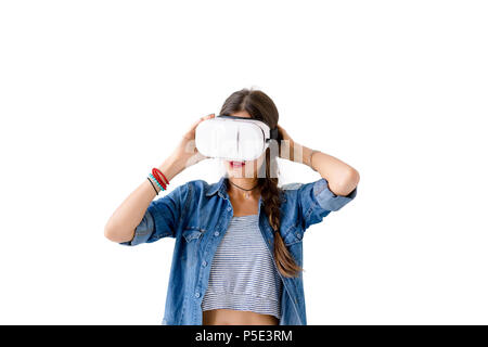 Portrait of determined young woman getting experience using VR glasses on white background. Beautiful girl touching VR device with hands while experie Stock Photo