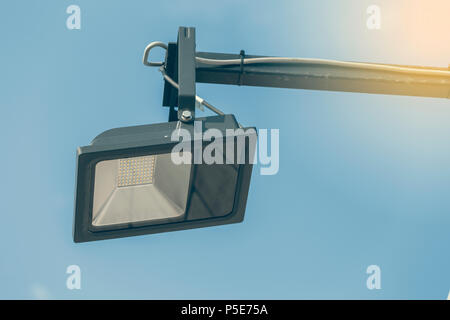 Outdoor single led street light with cable on sky background. Selective focus and vintage style. Stock Photo
