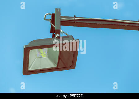 Outdoor single led street light with cable on sky background. Selective focus and vintage style. Stock Photo