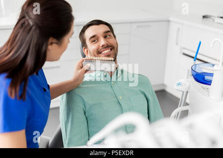 dentist choosing tooth color for patient at clinic Stock Photo