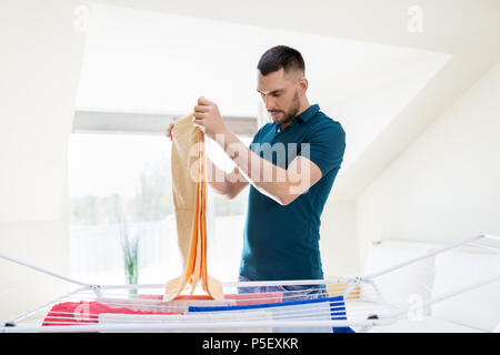 man taking laundry from drying rack at home Stock Photo
