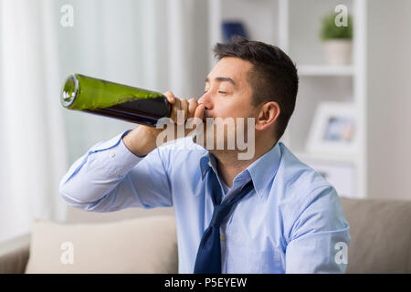 male alcoholic drinking wine from bottle at home Stock Photo