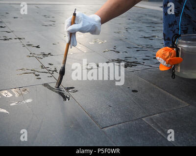 Older woman practicing calligraphy but due to the heat the Chinese  characters vanish instantly and not readable, Beijing, China Stock Photo