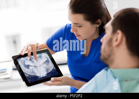 dentist and patient with teeth x-ray on tablet pc Stock Photo