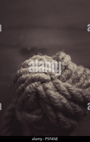 fender - marine knot of thick brown rope on a wooden background, closeup , toned Stock Photo