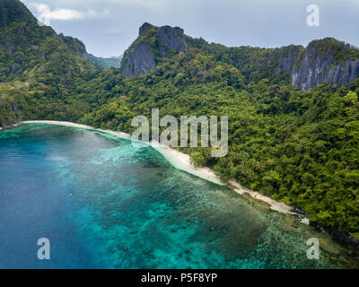 Aerial drone view of a beautiful deserted tropical beach surrounded by large cliffs and jungle (Cadlao Island, El Nido, Palawan) Stock Photo