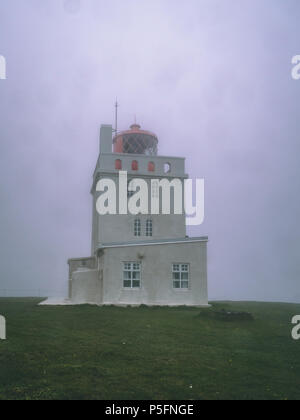 lighthouse covered in fog in iceland with red top, windows Stock Photo