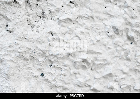 Rough Concrete Wall Decoration, Painted White. White Concrete Wall with Many Protruding Stones. Stock Photo