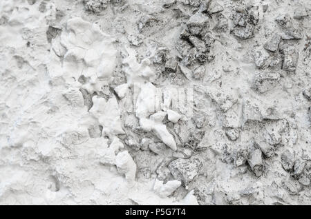 Rough Concrete Wall Decoration, Painted White. White Concrete Wall with Many Protruding Stones. Stock Photo