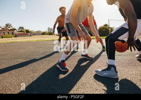 Men playing basketball game on a sunny day. Men practicing basketball skills in play area. Stock Photo