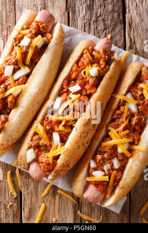 Chili hot dog with cheddar cheese and spicy sauce close-up on table. vertical top view from above Stock Photo