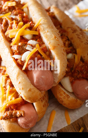 Chili hot dog with cheddar cheese and spicy sauce close-up on table. vertical Stock Photo