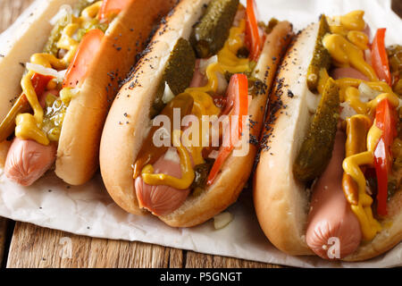 Chicago style hot dog with mustard, tomatoes, pickled cucumbers, onions and sauce close-up on the table. horizontal Stock Photo