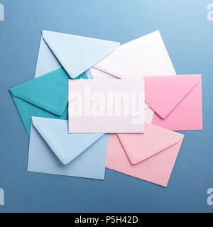 Group of colorful envelopes on grey table with empty card. Correspondence concept. Mockup. Stock Photo