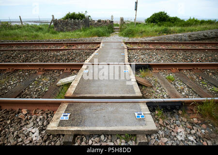 small unmanned pedestrian level crossing on coastal train track Cumbria England UK Stock Photo