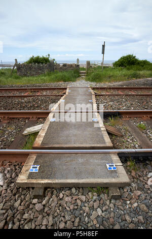 small unmanned pedestrian level crossing on coastal train track Cumbria England UK Stock Photo
