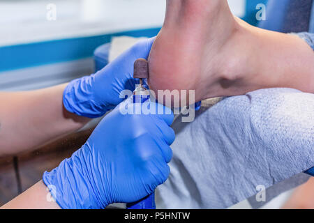 Master during a pedicure. The process of professional pedicures. The wizard in the mask causes the gel to the nails with a brush. The concept of beauty and health Stock Photo