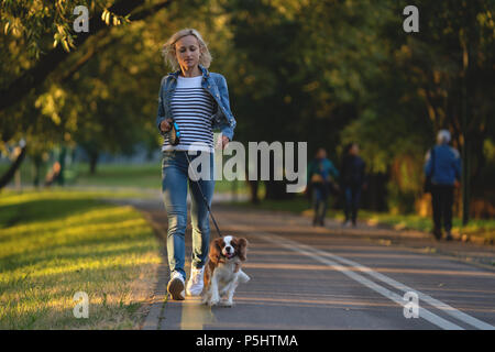 Beautiful young woman playing with her Dog in the Park in the autumn Stock Photo