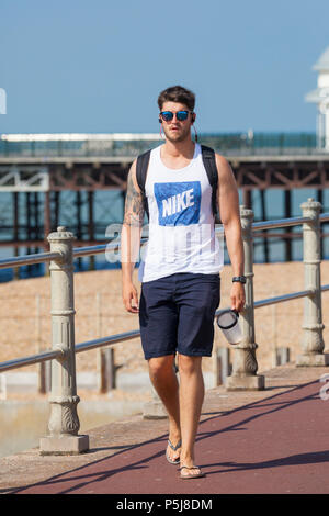 Hastings, East Sussex, UK. 27th Jun, 2018. UK Weather: The Hot and sunny weather continues in Hastings, East Sussex with highs of 30°C in some parts of the country. The heatwave that is hitting Britain is expected to last well into next week. Young man walking along the seafront wearing sunglasses. Photo Credit: PAL Images / Alamy Live News Stock Photo