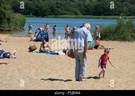 Frensham Pond, Surrey, UK. 27th June, 2018. The unbroken sunshine continues. Lots of sun-worshippers were enjoying themselves on the sand by Frensham Great Pond today, probably the closest thing to a beach in Surrey. Stock Photo