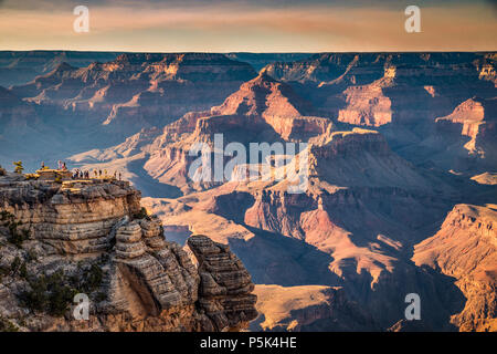 A group of hikers is standing on a steep cliff watching the sun set over famous Grand Canyon in summer, Grand Canyon National Park, Arizona, USA Stock Photo