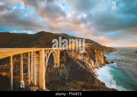 Scenic panoramic view of historic Bixby Creek Bridge along world famous Highway 1 in beautiful golden evening light at sunset with dramatic cloudscape Stock Photo