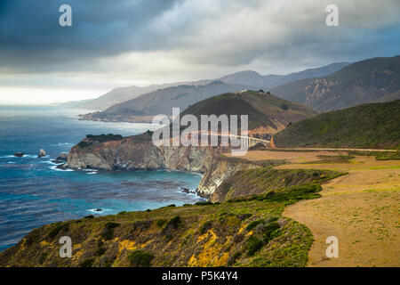 Scenic panoramic view of the beautiful coastline of Big Sur with historic Bixby Creek Bridge along world famous Highway 1 with dramatic cloudscape in 