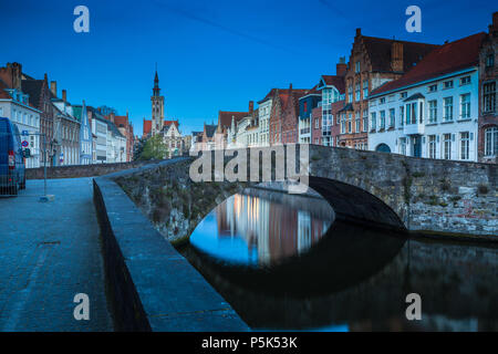 Beautiful panoramic view of famous Spiegelrei canal with famous Poortersloge and Jan van Eyck square in the background illuminated during blue hour at Stock Photo