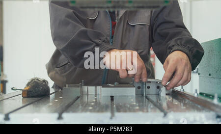 Worker with a scraper chamfering removing burrs on metal object for manufacturing industrial CNC machines Stock Photo