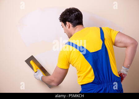 Young contractor employee applying plaster on wall Stock Photo