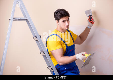 Young contractor employee applying plaster on wall Stock Photo
