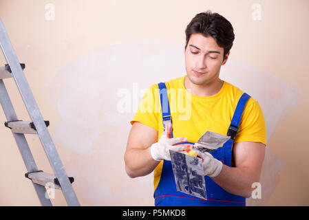 Young contractor employee applying plaster on wall Stock Photo