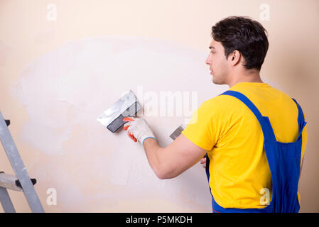 Young contractor employee applying plaster on wall Stock Photo