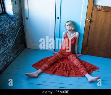 Blonde girl sitting on floor with penny board Stock Photo - Alamy