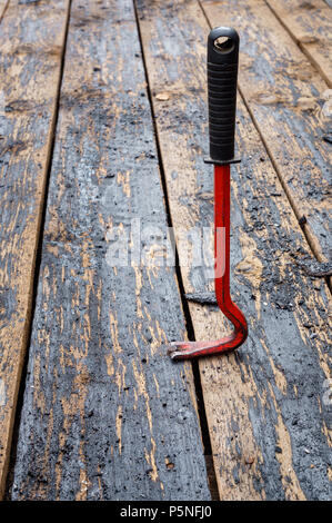 Red crowbar pulling a rusty nail to demonstrate the concept of leverage. Stock Photo