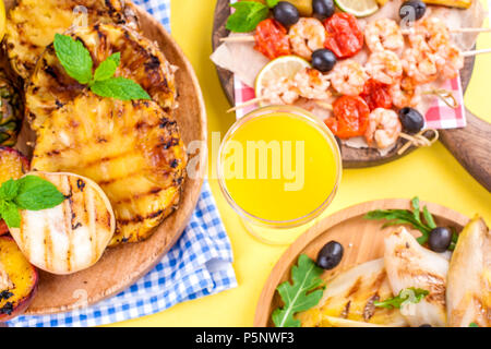 Different fruits and vegetables on grilled and shrimp. Yellow background. Summer dinner. Copy space Stock Photo