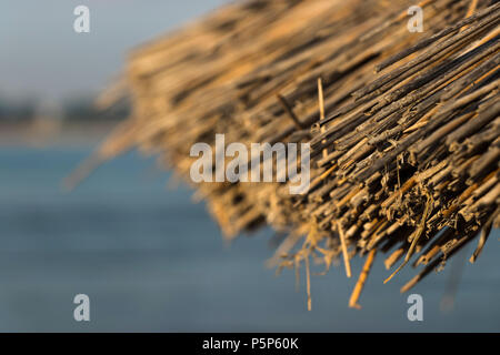 Straw umbrella on beach close up Stock Photo