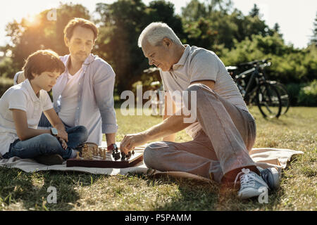 Happy family playing chess in nature Stock Photo
