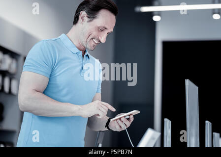 Pleasant young man standing with a smartphone Stock Photo