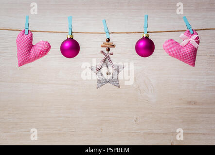 Christmas decorations and hearts hanging on rope on wooden background. Stock Photo