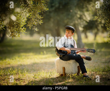 Young boy play on guitar at home at sunny day. Stock Photo