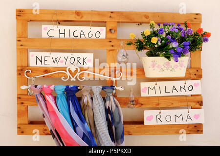 Pallet on wall with plant pots and colored foulards attached wooden pallets in San Felice Circeo, Lazio, Italy. World Destination Sign Directions to F Stock Photo